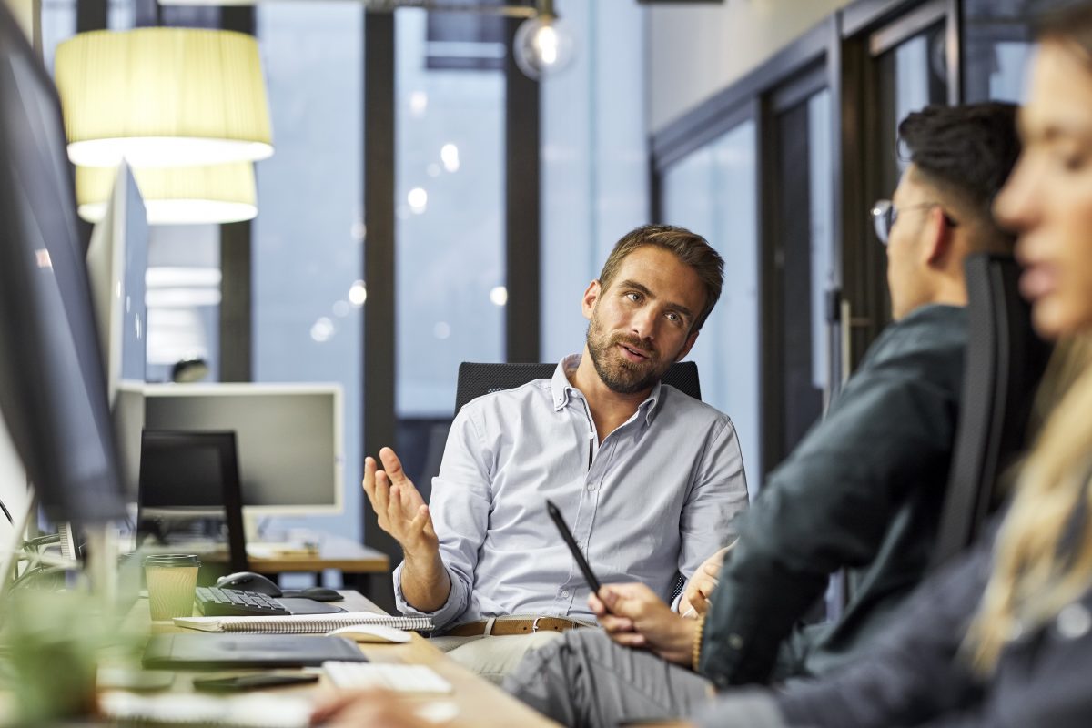Two office workers talking at desk
